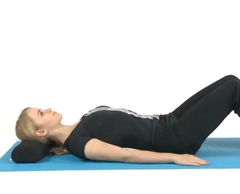 Woman laying on ErgoBack on a yoga mat, using a pillow