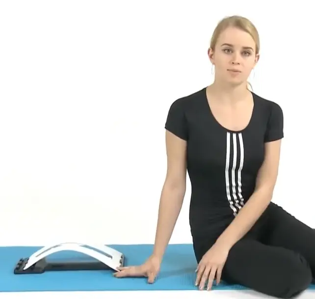 Woman siting next to ErgoBack on a training mat